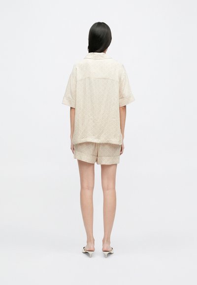 Béžový set krátkeho rukáva a nohavíc s jemným diamantovým vzorom. Ľahká tkanina s voľným strihom. Minimalistický dizajn.