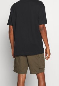 Svart bomull t-shirt med avslappnad passform och korta ärmar, i kombination med olivgröna cargoshorts med sidofickor.