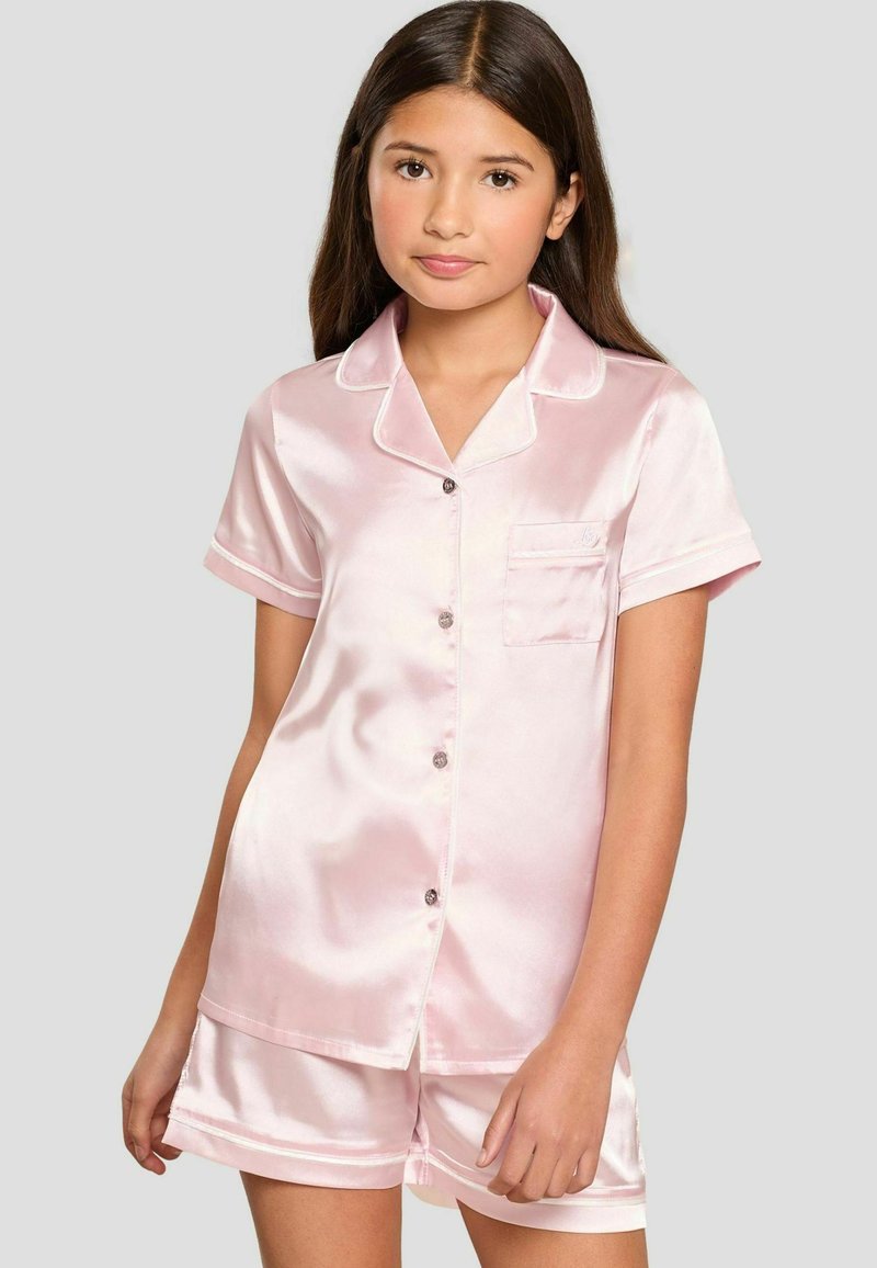 Conjunto de pijama de satén rosa claro que incluye una blusa de botones de manga corta con un bolsillo y pantalones cortos a juego; textura suave y detalles sutiles de ribete.