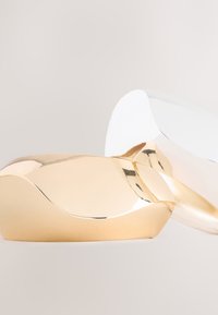 Gold- und silberfarbene Skulpturobjekte mit glatten, geschwungenen Oberflächen und reflektierenden Texturen, die ein modernes Design und organische Formen zeigen.