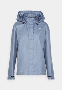 Chaqueta azul claro impermeable de Nike con capucha, mangas largas, cremallera frontal y correas ajustables en las muñecas.