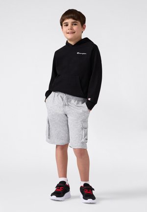 Black hooded sweatshirt with front pocket, paired with gray cargo shorts featuring side pockets. Black and red sneakers complete the look.