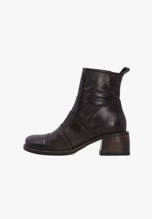 Dunkelbraune Lederstiefelette mit runder Zehenform, gestapeltem Absatz und überlappenden Designelementen im Obermaterial. Strukturierte Oberfläche mit Schlaufen-Tab.