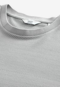Graues, strukturiertes T-Shirt mit einem gerippten Rundhalsausschnitt; mit einem diagonalen Muster und einem soliden horizontalen Streifen in der Mitte. Markenlabel sichtbar.