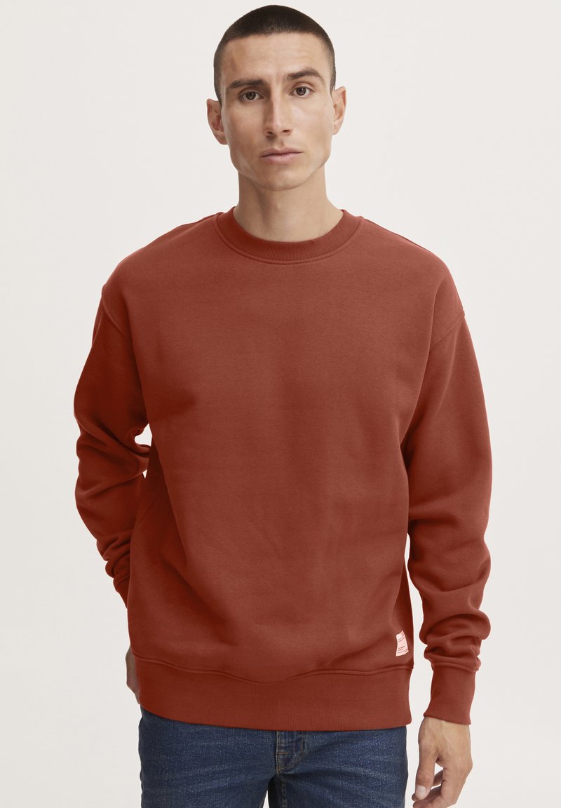 Roodbruine sweatshirt met een ronde hals, lange mouwen en geribde boorden. Bevat een klein geborduurd label op de linkeronderkant.