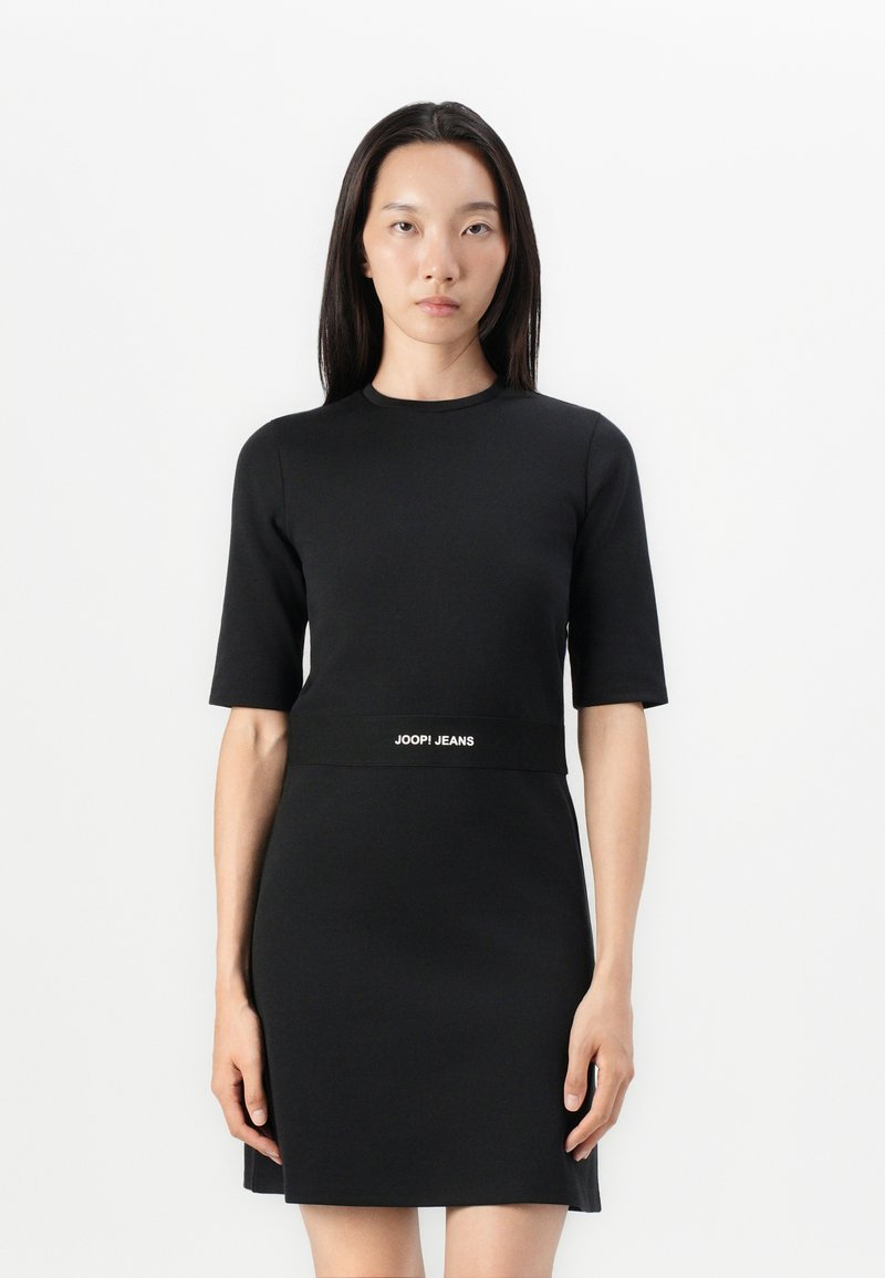 Rochie neagră, slim fit, cu mâneci scurte și decolteu înalt. Prezintă o bandă cu logo la talie și un material neted, texturat.