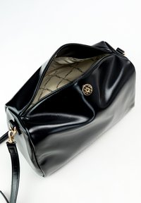 Borsa sintetica nera e lucida con una forma curva, apertura con zip superiore, fodera interna beige e dettaglio con bottone dorato.