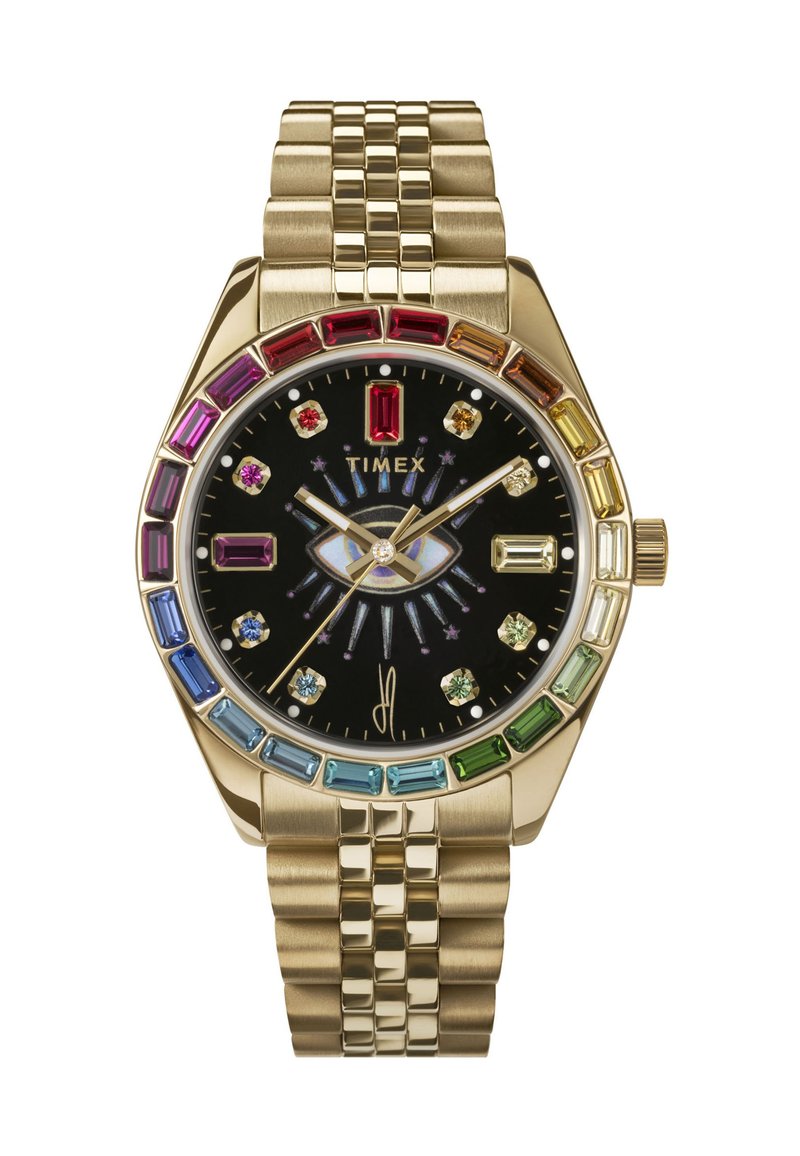 Ceas din metal cu ton de aur, cu un cadran negru, accente colorate din cristale și o brățară texturată. Prezintă un design unic în formă de ochi pe cadran.