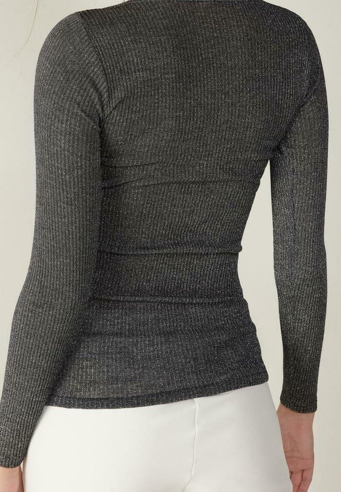 Slim fit, långärmad, ribbad, mörkgrå topp som bärs med vita byxor, visad från baksidan mot en ljus bakgrund.