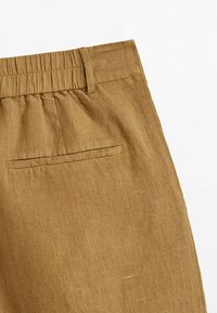 Braune Leinenhose mit elastischem Bund, ausgestattet mit einer hinteren Tasche mit genähtem Rand. Der Stoff hat eine strukturierte Optik.