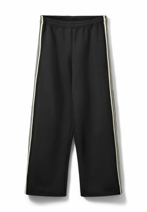 Pantaloni de trening negri cu talie elastică, având două dungi verticale albe de-a lungul cusăturilor laterale. Confecționați dintr-un material neted și moale.