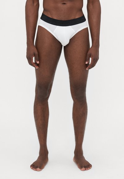 Culotte blanche pour hommes avec une taille noire, présentant une texture à motif. Le design est classique avec une coupe ajustée et en coton.