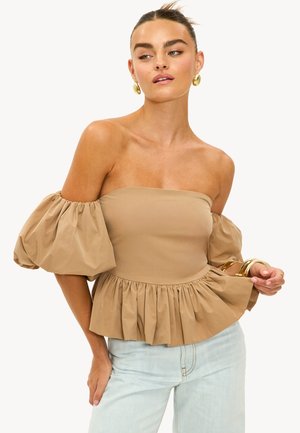 Haut tan à épaules dénudées avec des manches bouffantes, taille froncée et ourlet à volants. Fabriqué en tissu mélangé de coton. Associé à des accessoires dorés.