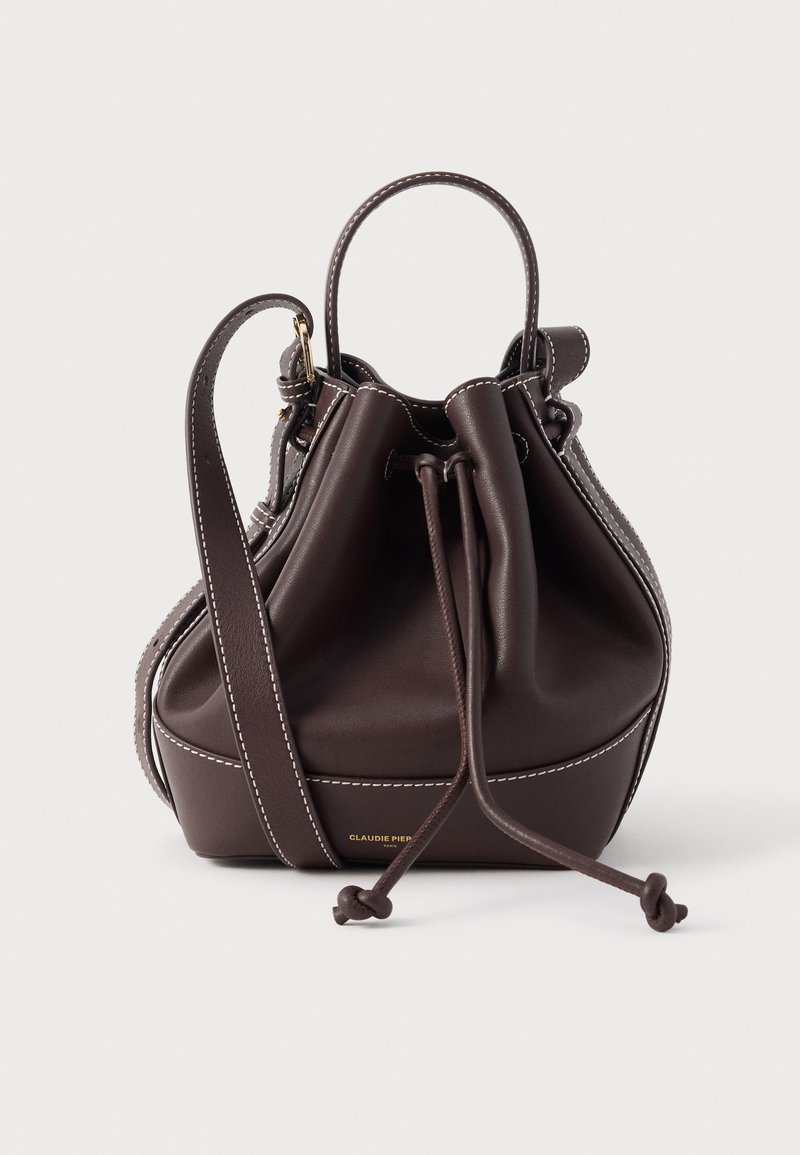 Hnedá kožená kabelka typu bucket s kontrastným bielym prešívaním, okrúhlym dnom, zaväzovaním na šnúrku a dvoma rukoväťami. Zlatožlté logo vpredu.