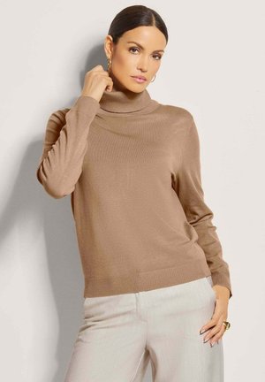Hellbrauner Rollkragenpullover mit gerippten Bündchen und Saum. Weiche Textur, lange Ärmel, taillierte Passform. Kombiniert mit hellen Hosen.