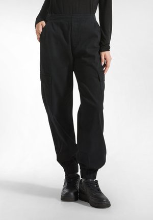 Black cargo pants with an elastic waistband, ribbed cuffs, and side pockets. Made of a durable fabric with a smooth texture.