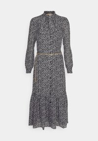 Svart-och-vitt blommönstrad klänning med lång ärm, hög krage och en flerlagers volangnederdel, åtdragen i midjan med ett guldigt bälte.