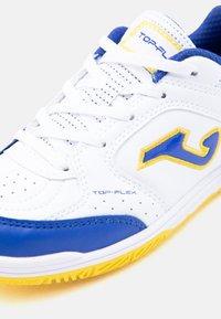 Λευκό αθλητικό παπούτσι με μπλε και κίτρινες λεπτομέρειες, λευκά κορδόνια, διάτρητες λεπτομέρειες και κείμενο «Top-Flex» στο πλευρό και τη γλώσσα.