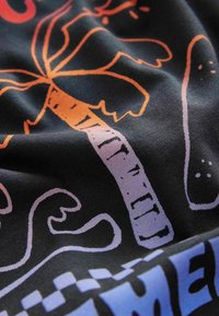 Black fabric features colorful graphics, including a palm tree in orange, waves, and abstract shapes in purple and blue.