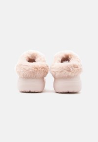Rózsaszín puha papucsok, puhán bolyhos textúrával és lekerekített hátoldali kialakítással. Párnázott talpbetét a kényelemért, beltéri viseletre alkalmasak.