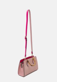 Różowa i beżowa torebka o strukturalnym kształcie z odpinanym jasnoróżowym paskiem, bambusowym uchwytem, złotymi akcentami i kontrastującymi czarnymi wykończeniami.