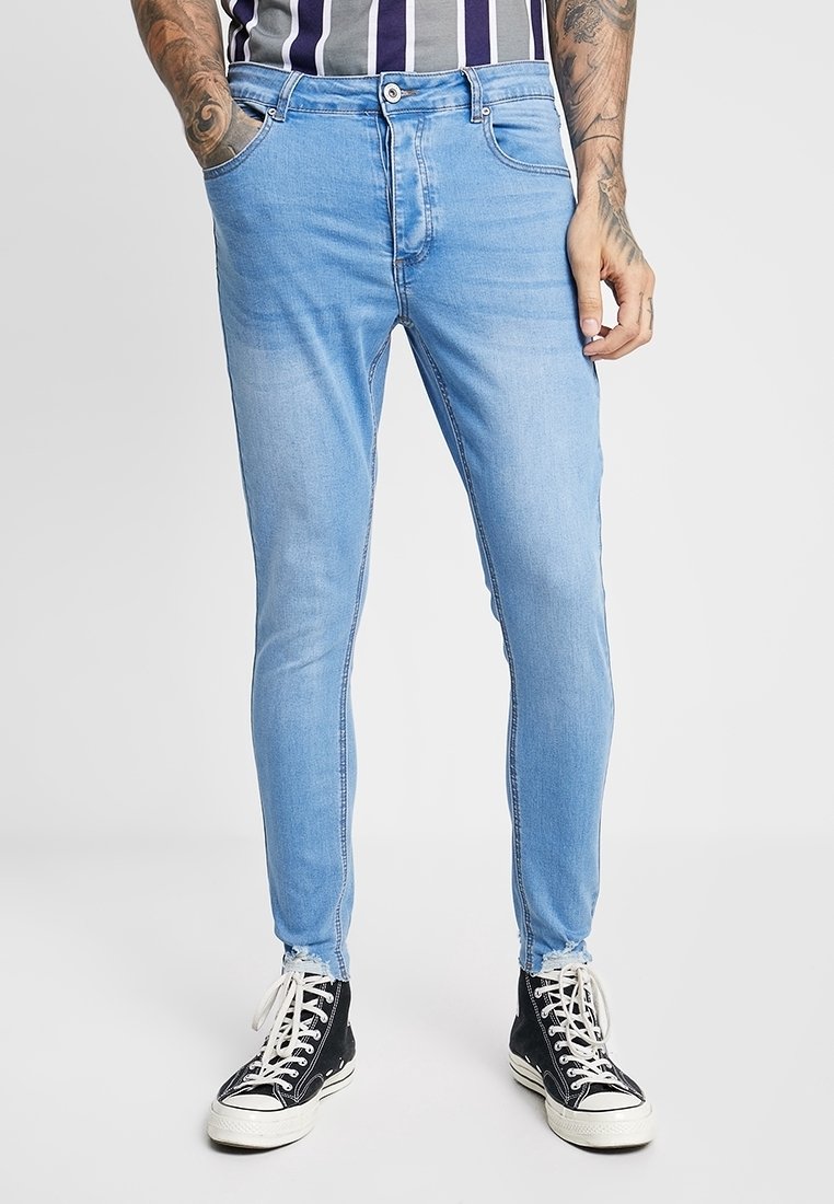 Jeans ajustados de color azul claro en tejido de denim, que incluyen un cierre frontal con botón, dos bolsillos laterales y un ligero desgaste para dar textura.