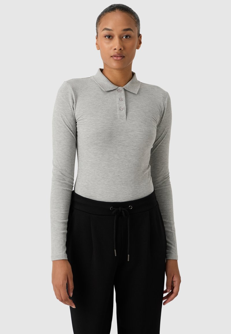 Jasnoszara, długorękawowa koszulka polo o prążkowanej strukturze, z trzema guzikami przy kołnierzyku, zestawiona z czarnymi spodniami na sznurek.