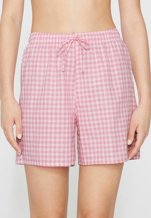 Frau trägt rosa-weiß karierte Shorts mit elastischem Bund und vorderem Kordelzug, von der Taille bis zum Oberschenkel gezeigt.