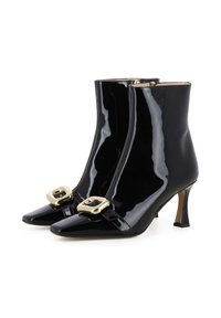 Bottines en cuir verni noir avec un bout pointu, présentant un détail de boucle dorée à l'avant et un talon fin. Texture lisse et brillante.