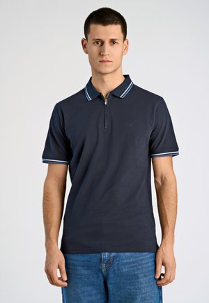Camisa polo en color navy con cremallera de un cuarto, que presenta acentos a rayas en blanco y azul claro en el cuello y las mangas. Tela de mezcla de algodón.