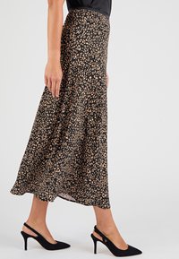 Gonna midi nera con motivo leopardato in beige, realizzata in tessuto leggero; presenta una silhouette fluida e una vita alta.
