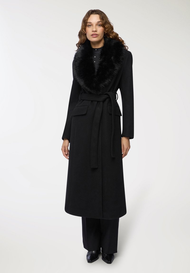 Cappotto di lana nera con colletto in pelliccia sintetica, vita con cintura, tasche frontali e maniche lunghe. Tessuto liscio con un design elegante.