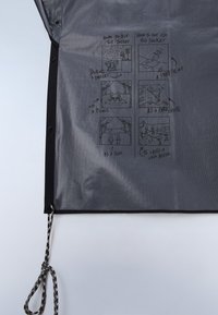 Grå jakke med sorte knapper og en trykt tegneserie, der viser korrekte og ukorrekte måder at bruge jakken på i seks små felter.