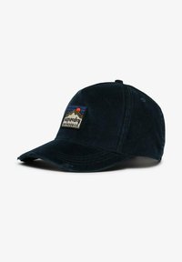 Gorra de pana azul marino con visera curva, que presenta un parche cosido con montañas y un sol, y el texto de marca "superdry outdoor co."