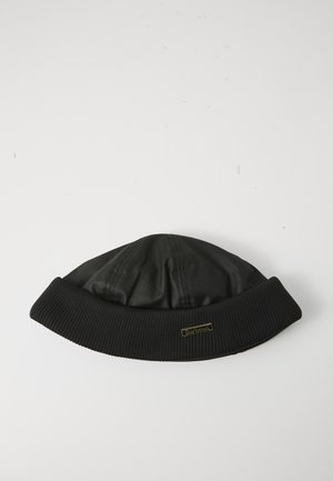 Zwarte Barbour beanie muts met geribde omslagrand en klein gouden logo op een effen witte achtergrond.
