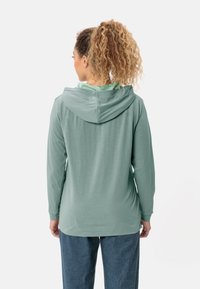 Langärmliges Kapuzenshirt aus weichem grünen Stoff mit einem schlichten Design, bestehend aus einer Kapuze, geradem Saum und lockerer Passform.