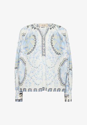 Blouse blanche à manches longues avec motifs floraux et circulaires bleus, patte de boutonnage et bordure décorative noire autour du col et de l'ourlet.