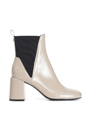 Stivale alla caviglia in pelle sintetica beige con tacco a blocco, pannello elastico laterale nero, punta affusolata e dettaglio con zip sul retro.