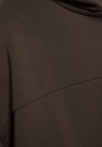 Barna szövet, sima textúrával és diszkrét fénylással, varrással, amely geometriai mintát alkot.