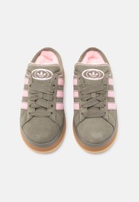 Ténis de camurça verde-azeitona com riscas e atacadores cor-de-rosa, forrados interiormente com polar rosa e sola exterior em borracha cor de goma. Design clássico com detalhe do logótipo.