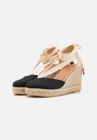 Czarne płócienne buty na koturnie z jutową podeszwą i beżowymi paseczkami. Wewnętrzna wkładka w kwiatowy wzór oraz fakturowane wykończenie z tyłu.