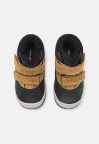 Zwarte en tan kinderschoenen met twee klittenbandsluitingen, suede accenten, een gestructureerde voering en een rubberen zool, met een logo aan de binnenkant.