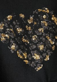 Tissu noir ornés d'un motif de cœur en sequins dorés et noirs, de tailles et textures variées, créant un effet scintillant.