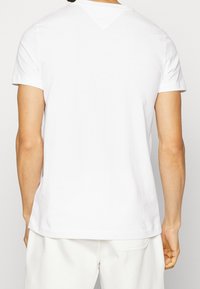 Biała koszulka z krótkim rękawem wykonana z bawełny, z okrągłym dekoltem i prostym krojem, z minimalnymi detalami przeszycia z tyłu.