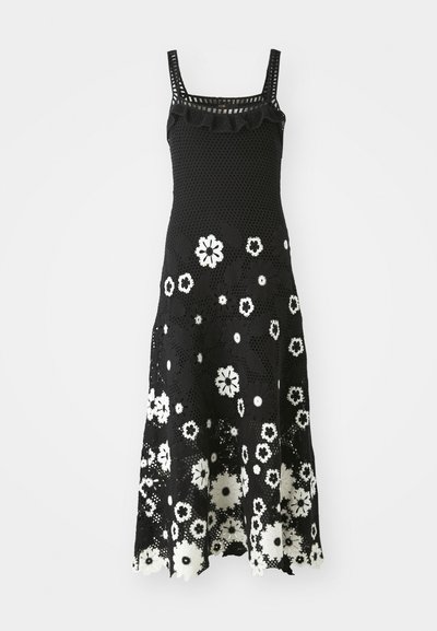 Fekete horgolt ruha négyzet alakú dekoltázzsal, fodros részletekkel és fehér virágmintával. Szélesített szegő és bonyolult csipkés textúra.