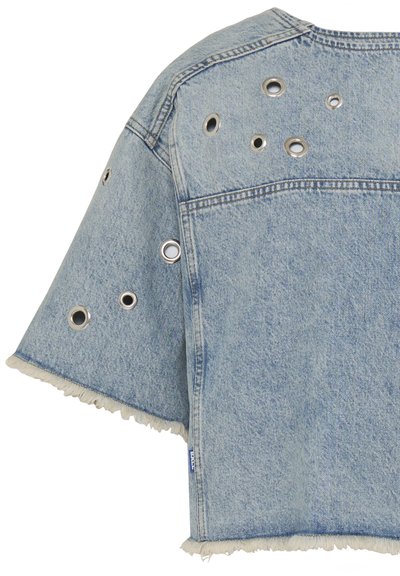 Veste en denim bleu clair à manches courtes avec ourlets effilochés et œillets métalliques argentés de différentes tailles dispersés sur le dos et la manche.