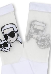 Calzini bianchi realizzati in materiale trasparente, con una grafica in bianco e nero che rappresenta una figura con occhiali da sole. Alternanza a coste nella parte superiore.