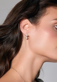 Srebrne kolczyki ozdobione okrągłą perłą i dekoracyjnym akcentem z cyrkonii, prezentujące delikatny i elegancki design.