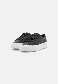 Svarte lærersneakers med hvit gummisåle, rundt tåparti og flate lisser. Har merkevarenavn på siden og polstret krage for komfort.