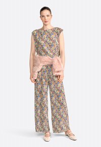 Multicolored, pleated fabric outfit with a loose-fitting top and wide-leg pants; features a soft, pink fur accent around the waist.